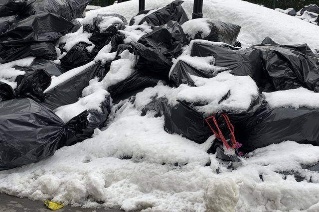 Piles of black garbage bags under snow in NYC.